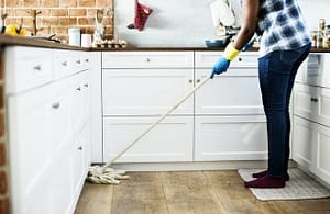 Picture of woman with gloves on mopping the kitchen floor