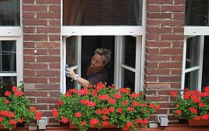 Picture of woman cleaning windows in front of red flower box